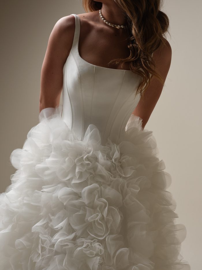 Close-up of Sottero and Midgley Ross wedding dress featuring a sleek square neckline, boned corset-style bodice, and textured organza ruffle detailing on the full ballgown skirt.