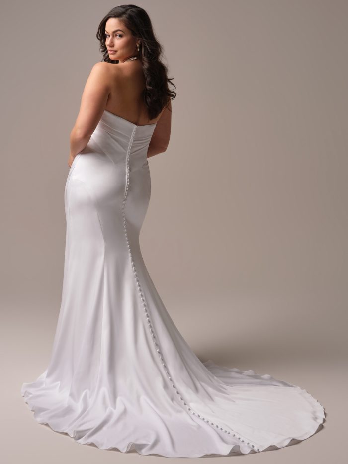 Back view of a strapless satin sheath wedding dress with a V-cut back and a row of buttons cascading down the train.