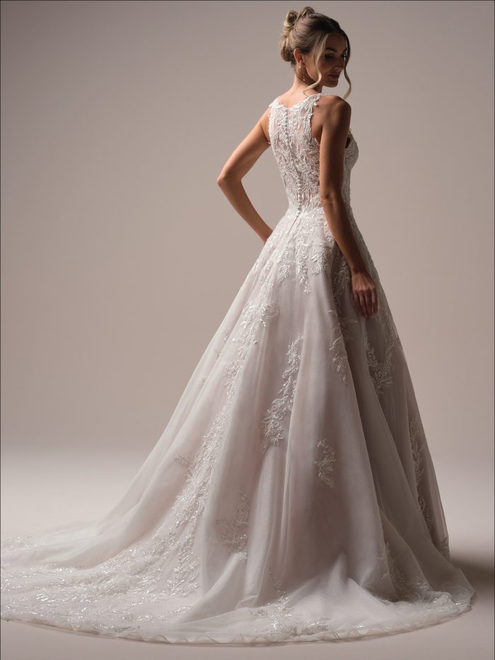 Back view of an A-line wedding dress with a high illusion neckline and intricate lace embroidery cascading through the tulle skirt and train.
