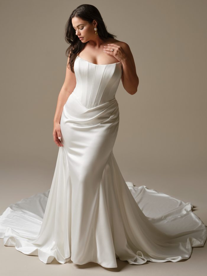 inclaire by Maggie Sottero satin fit-and-flare wedding dress with a corset-inspired bodice, strapless neckline, and softly draped skirt with a flowing train