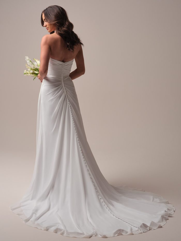 Back view of a strapless chiffon A-line wedding dress featuring soft ruching, a row of covered buttons, and a gentle train with flowy movement.