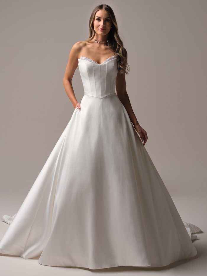 Front view of a strapless satin wedding dress featuring a structured corset-style bodice with exposed boning and a pearl-beaded neckline.