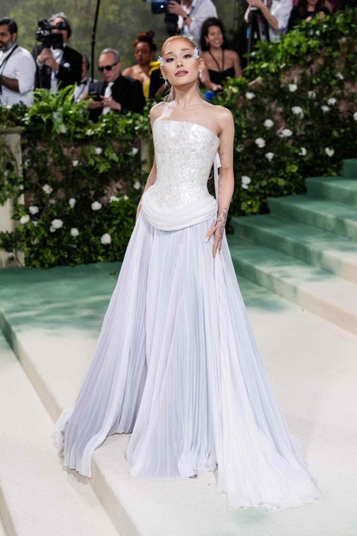Ariana Grande wearing a Strapless white corset-style gown with an iridescent textured bodice and soft draped waist detail, paired with a pleated skirt at a formal red carpet event