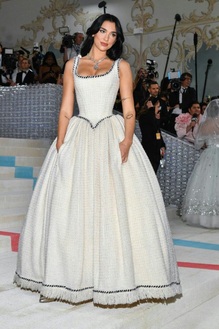 Dua Lipa wearing a White vintage-inspired ballgown with a sculpted basque waist, square neckline, and full skirt, styled with corded details at a formal red carpet event