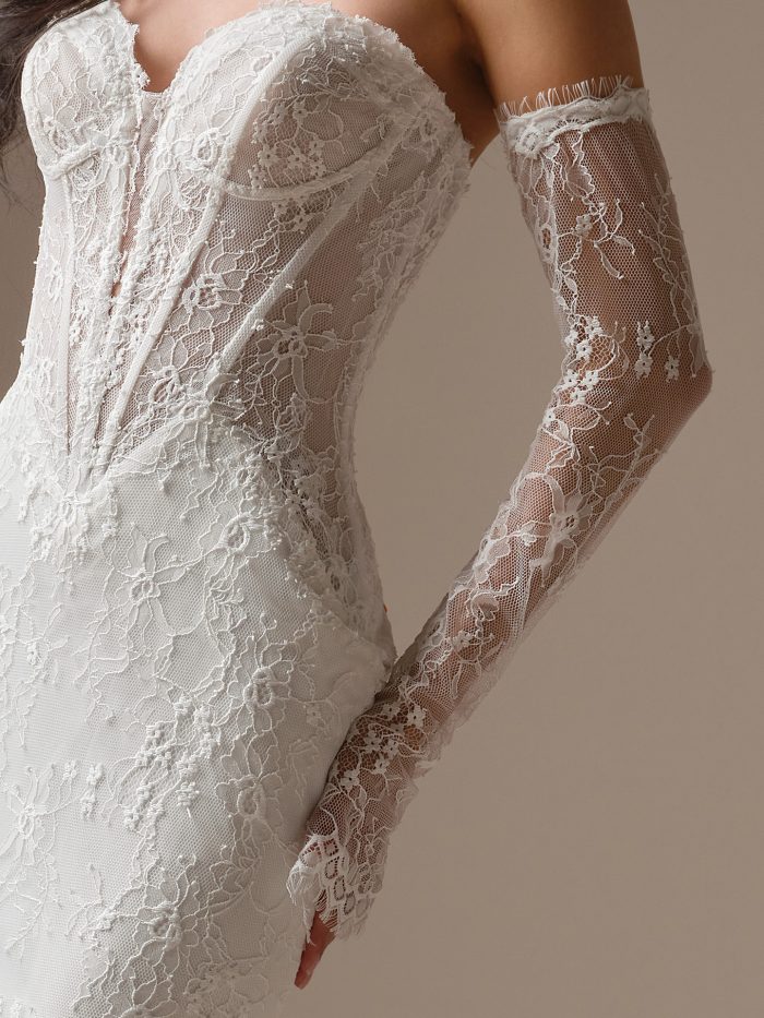 Close-up view of the Bellevue wedding dress showing Chantilly lace, exposed boning along the illusion bodice, scalloped sweetheart neckline, and detachable lace arm sleeves with floral detailing.