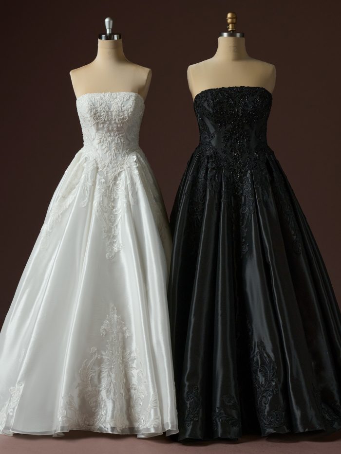 Two Dahlia ballgown wedding dresses by Maggie Sottero displayed on mannequins, showcasing strapless lace-embellished bodices in ivory and black with full satin skirts and ornate embroidery.