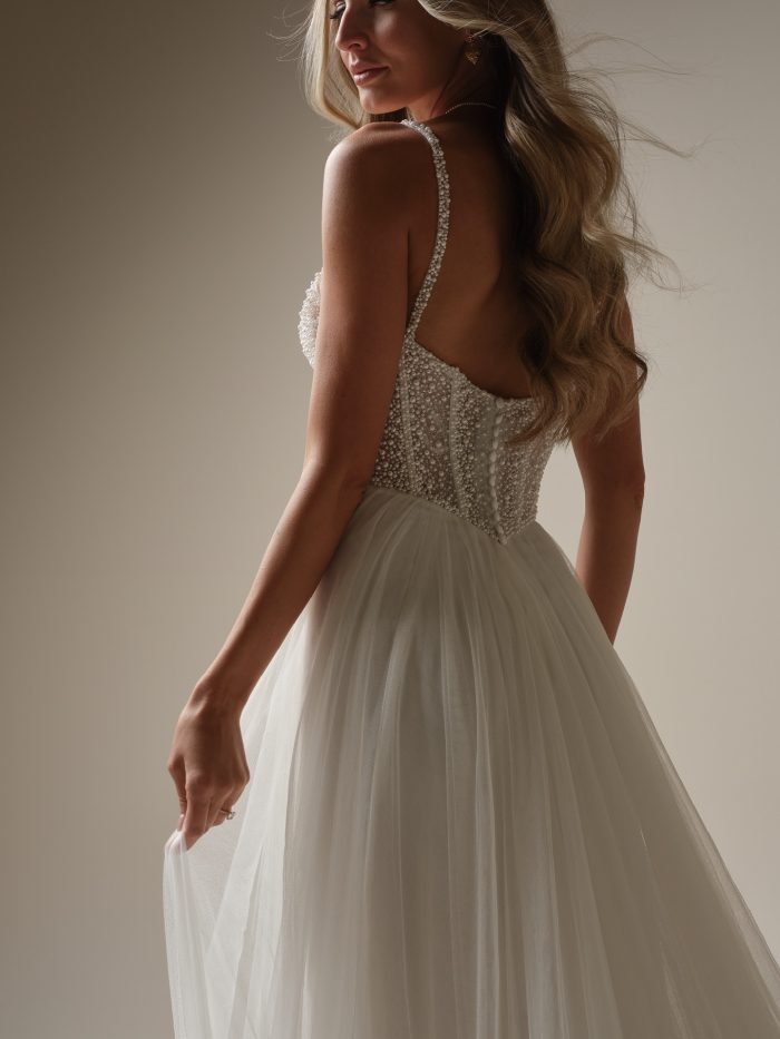 Back view of the Maggie Sottero Gretchen wedding dress showcasing the pearl-embellished bodice, delicate straps, and a soft layered tulle skirt with airy movement.