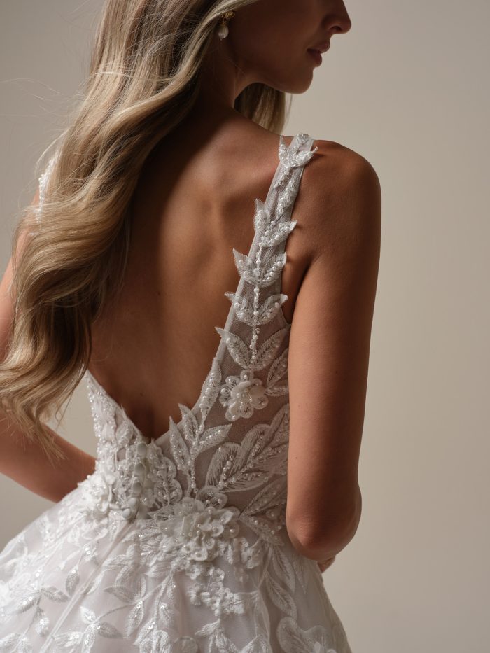 Back view of the Maggie Sottero Magnolia wedding dress showcasing an illusion lace bodice with pearl and sequin beading, delicate floral appliqués, and a low scoop back with covered buttons.