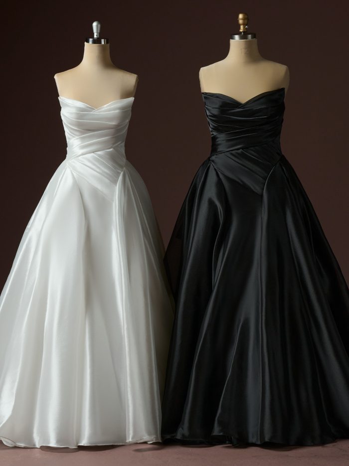 Two Rosamund A-line wedding dresses by Maggie Sottero displayed on mannequins, featuring strapless ruched bodices with softly draped satin and full A-line skirts in ivory and black.
