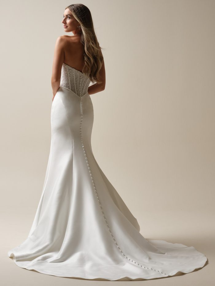 Back view of the Maggie Sottero Tina Marie fit-and-flare wedding dress showcasing a pearl-beaded corset bodice, satin skirt, and covered buttons trailing down the train.