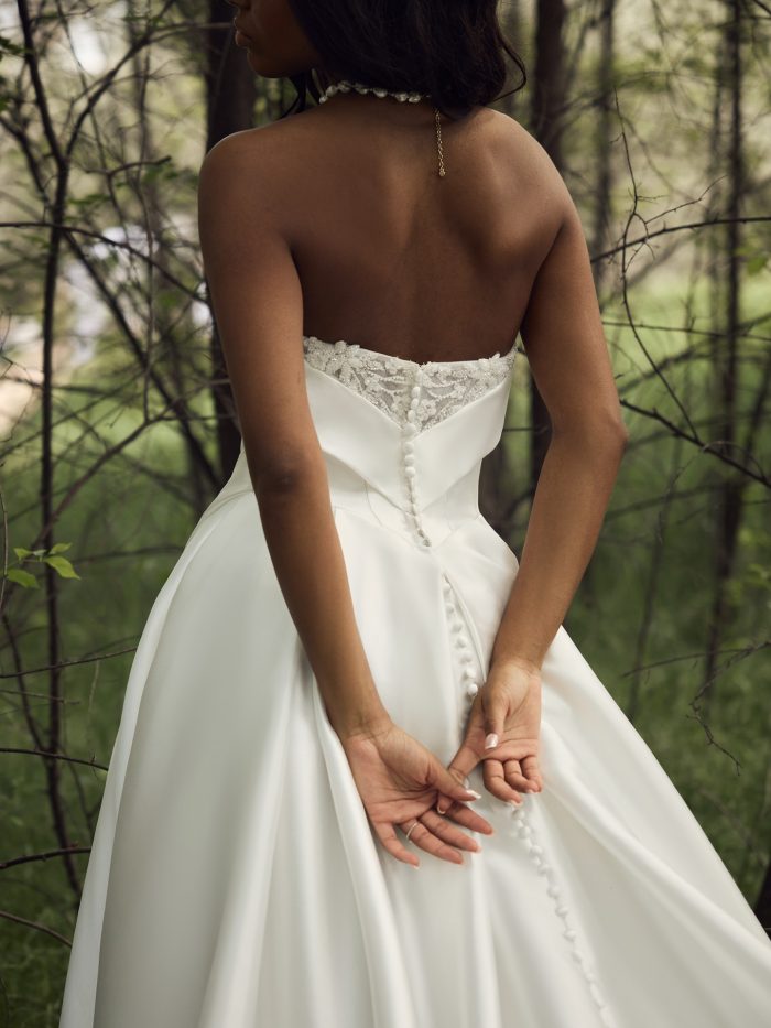 Close-up back view of a bride in the Agatha A-line wedding dress by Rebecca Ingram, showcasing the illusion lace button-back detail and fitted bodice.