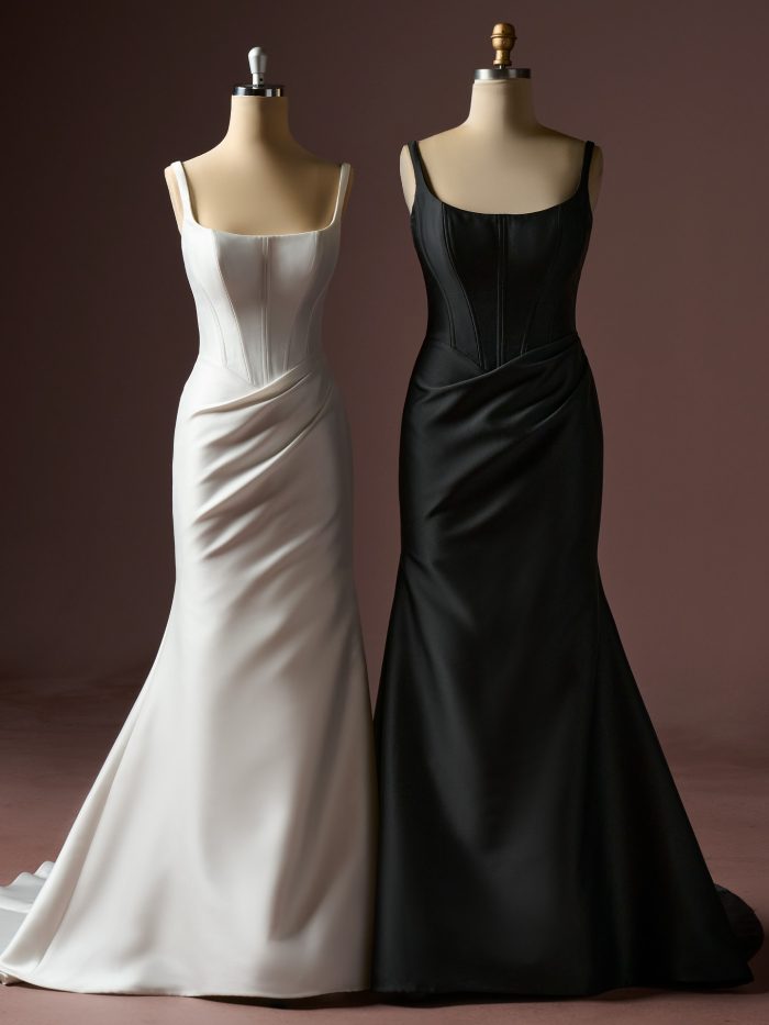 Two Pamela fit-and-flare wedding dresses by Rebecca Ingram displayed on mannequins, featuring square necklines with wide straps, structured corset bodices, and softly draped skirts in ivory and black satin.