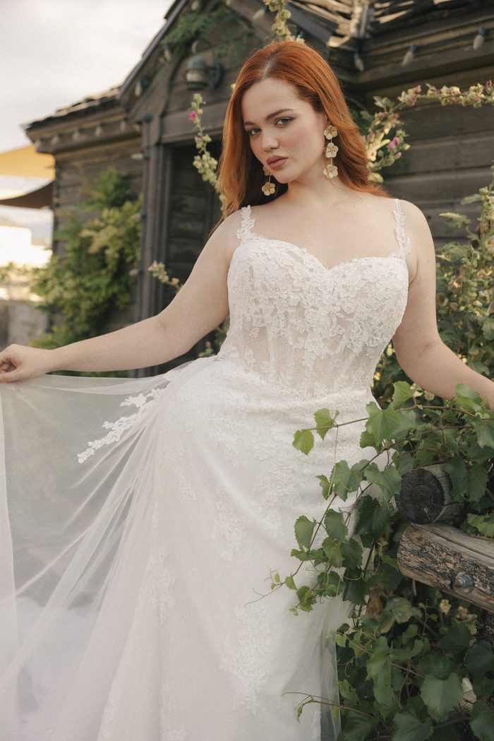 Esmeralda Lane boho floral wedding dress featuring 3D lace appliqués, delicate spaghetti straps, and a sheer corset bodice in a romantic outdoor setting.