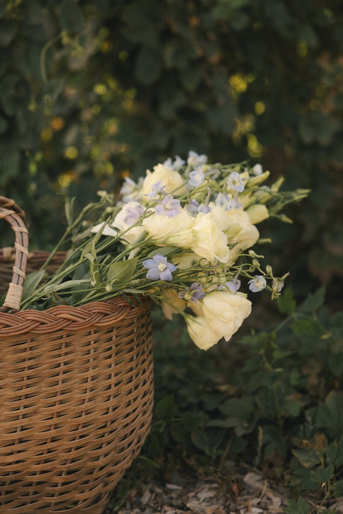 Basket of fresh garden flowers featuring ivory blooms and delicate lavender accents, styled as romantic floral inspiration for a boho wedding aesthetic.