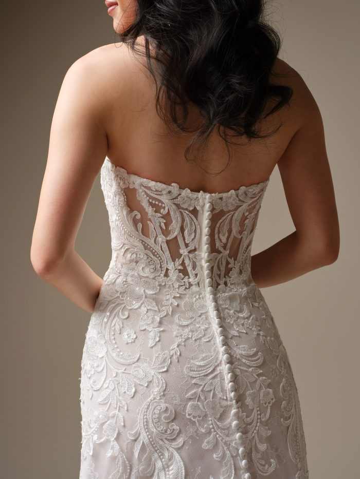 Back view of Farrah by Maggie Sottero, featuring an illusion lace bodice with covered buttons and intricate embroidered detailing along the train.