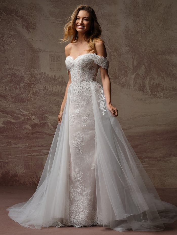Esmeralda Lane boho floral wedding dress with a detachable tulle overskirt train, featuring romantic floral lace appliqués, an off-the-shoulder neckline, and a versatile two-in-one bridal look.