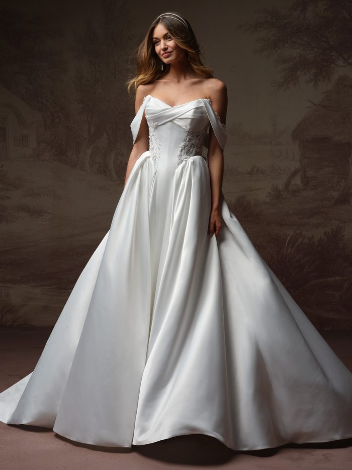 Gigi ballgown wedding dress with detachable cap sleeves, featuring a draped strapless neckline, lace-accented corset bodice, and a voluminous satin skirt for a romantic boho-inspired bridal look.
