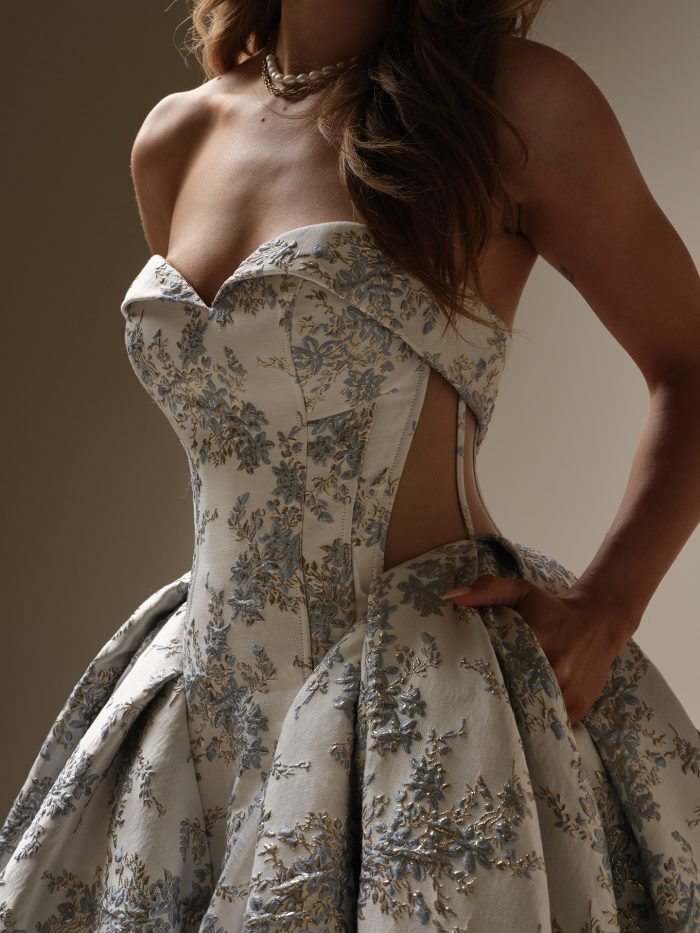 Close-up of Aberdeen by Sottero and Midgley showcasing the folded sweetheart neckline, structured corset bodice with exposed boning, illusion side panel, and intricate blue floral jacquard fabric.