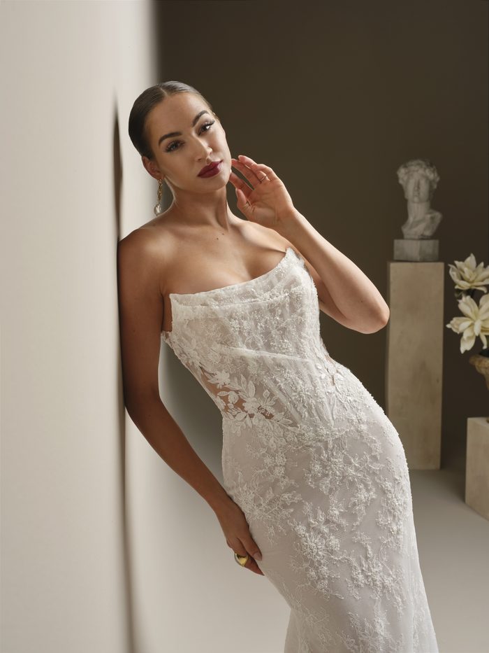 Dublin boho lace fit-and-flare wedding dress showcasing a draped off-the-shoulder neckline, sheer illusion corset bodice, and allover floral lace detailing in a sleek, fitted silhouette.