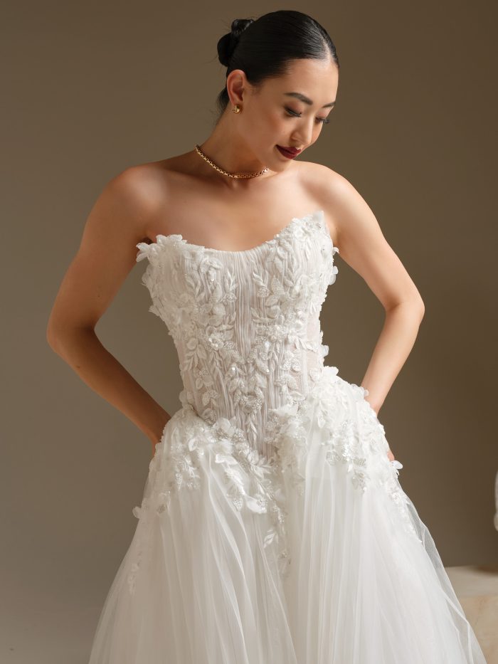 Close-up of Jayna by Sottero and Midgley, a strapless ball gown wedding dress featuring a sheer pleated tulle bodice with 3D floral lace appliqués and exposed boning.