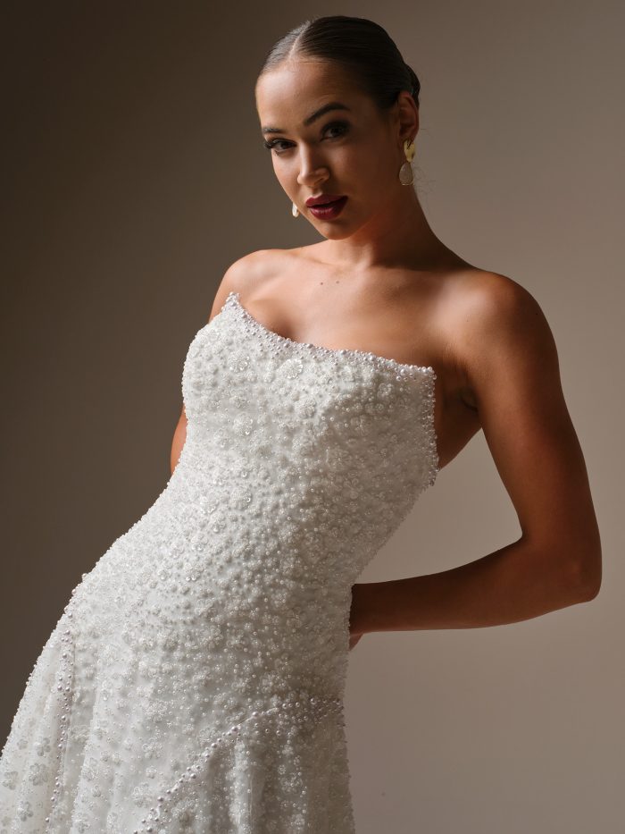 Close-up of Sottero and Midgley Marceline wedding dress bodice with asymmetrical strapless neckline and dimensional floral beaded details.
