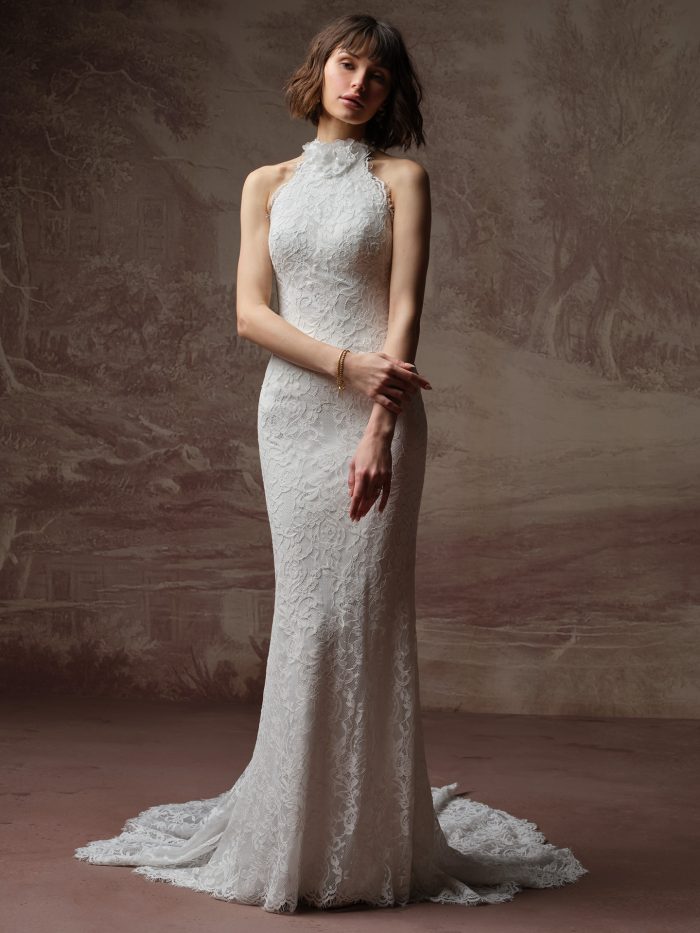 Front view of a bride wearing the Anya lace sheath wedding dress with a high halter neckline, floral appliqué detail at the collar, and a fitted lace skirt with lace train.