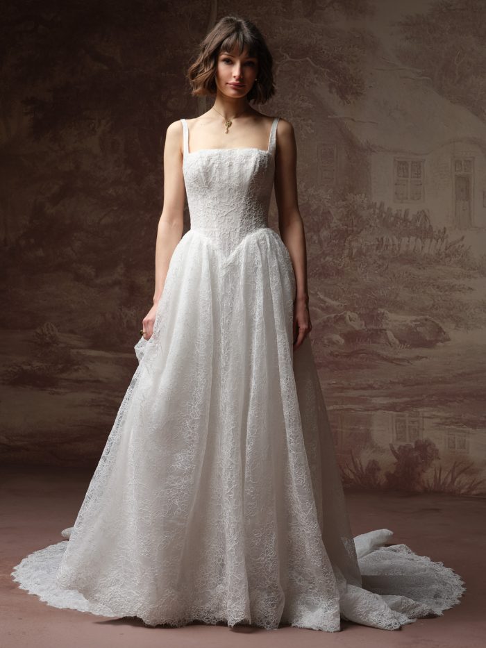 Front view of a bride wearing the Autumn ballgown wedding dress in lace, featuring a square neckline with thin straps, a fitted lace bodice, and a full lace ballgown skirt with train.