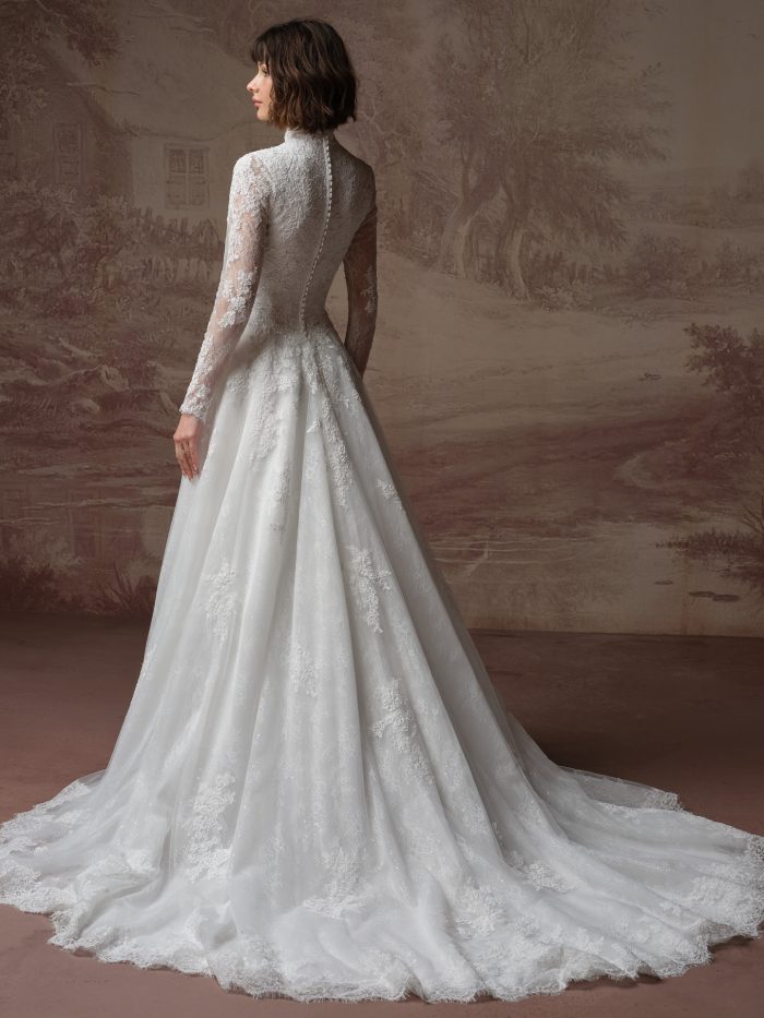Back view of a bride wearing the Dominique ballgown wedding dress, showing a high sheer lace back with a row of covered buttons, long lace sleeves, and a full lace skirt sweeping into a scalloped train.