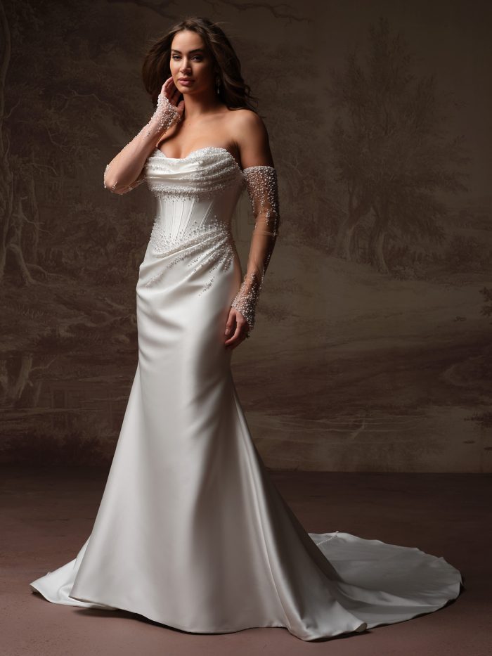 Front view of a bride wearing the Melissa Royale fit-and-flare wedding dress in satin, featuring a strapless pearl-beaded bodice, off-the-shoulder pearl-embellished sheer sleeves, and a sweeping train.