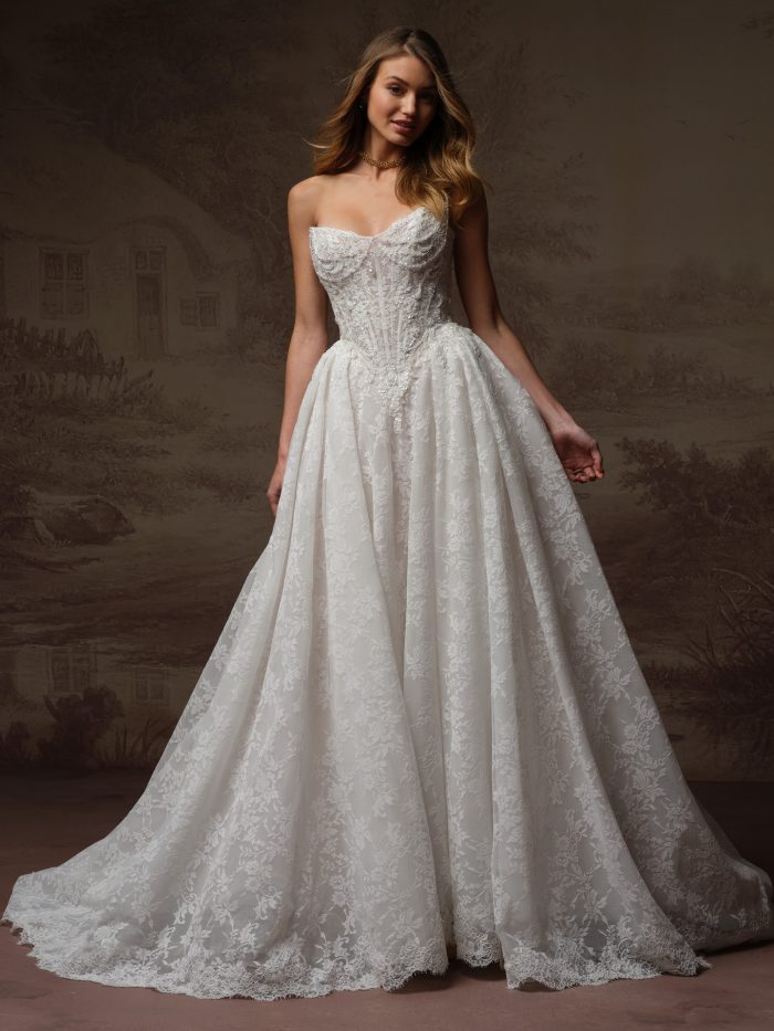 Front view of a bride wearing the Ryland ballgown wedding dress, featuring a strapless beaded sweetheart bodice with corset boning and a full lace ballgown skirt with scalloped train.