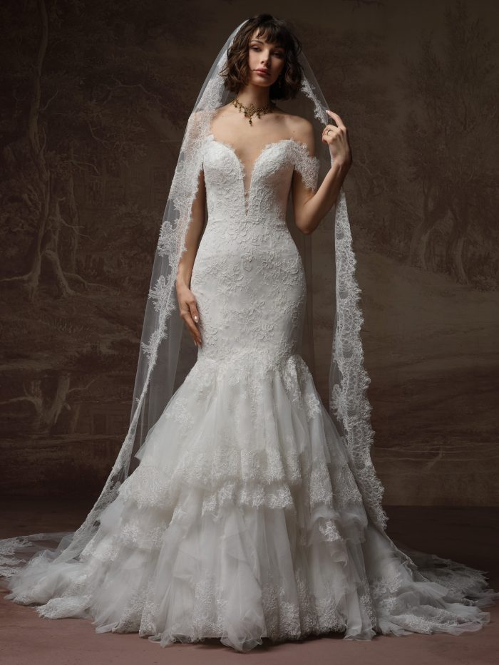 Front view of a bride wearing the Sauvignon cathedral veil with scalloped lace trim framing the face and shoulders, paired with an off-the-shoulder lace mermaid wedding dress with tiered ruffled skirt.