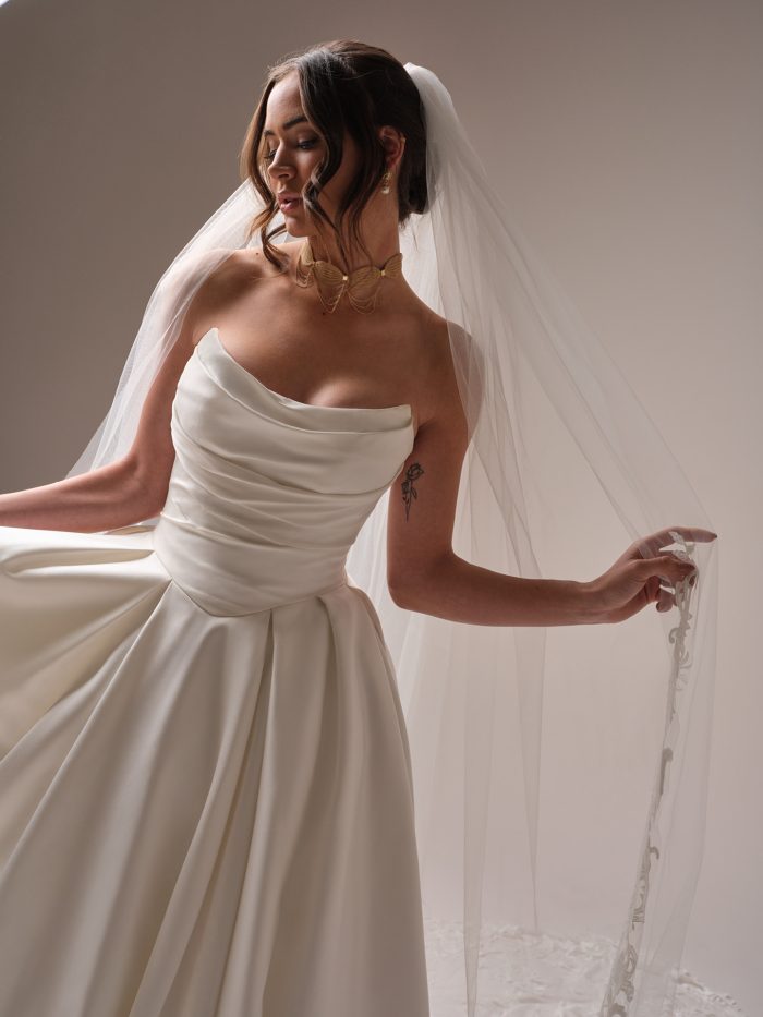 Close-up of the Maureen veil by Maggie Sottero, showing the lace-trimmed edge over a strapless draped satin wedding gown.