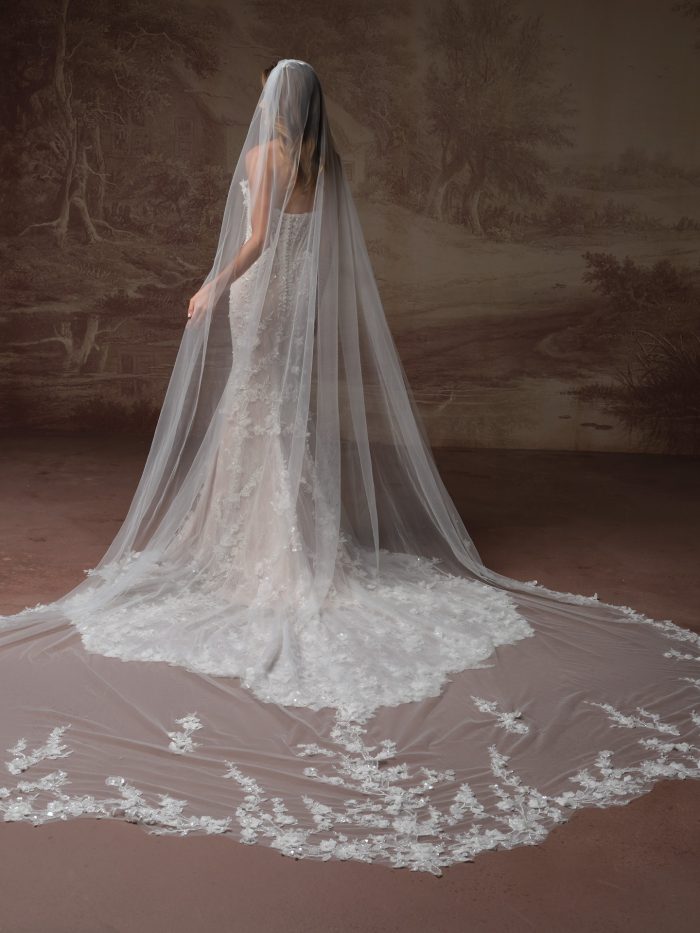 Back view of the Stasia wedding dress by Maggie Sottero, showing the button-back bodice and floral lace mermaid train with a matching lace-appliquéd cathedral veil.