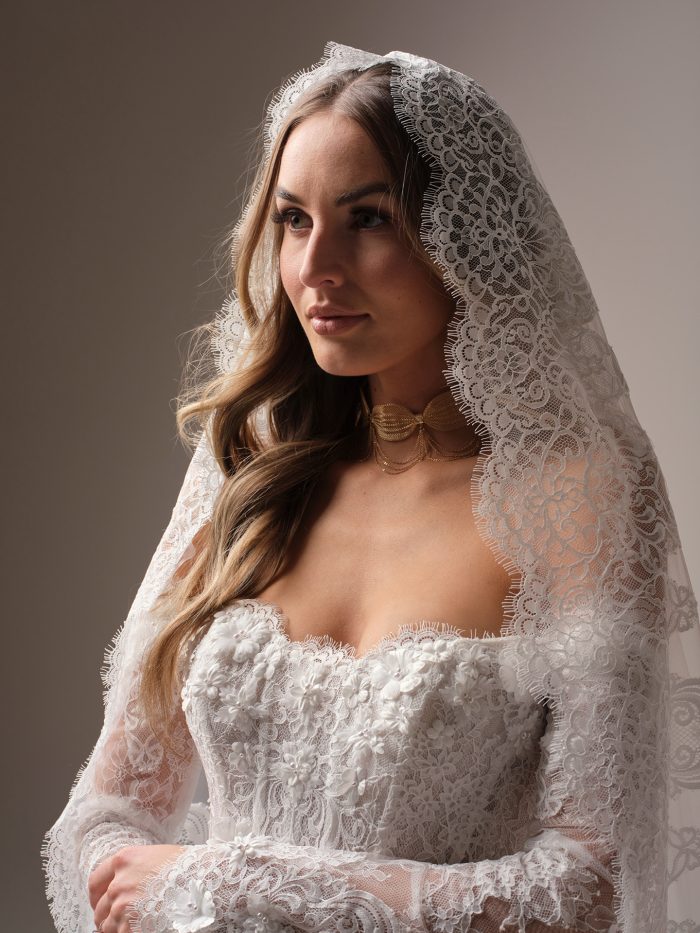 Close-up of the Takera veil by Maggie Sottero, showing the intricate scalloped floral lace draped over a lace long-sleeve wedding gown.