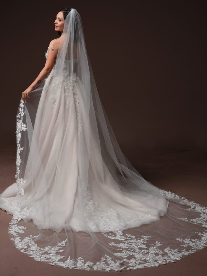 Back view of the Fleur wedding dress by Rebecca Ingram, featuring a strapless lace-appliquéd A-line gown paired with a cathedral veil edged in floral lace appliqué.
