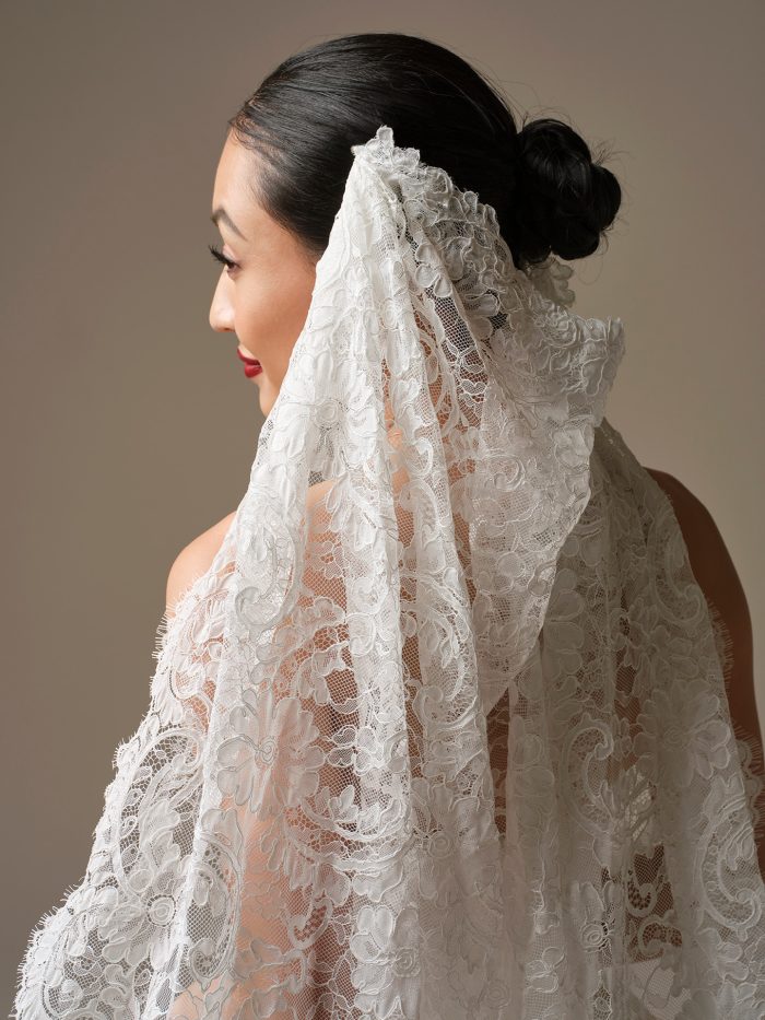 Close-up back view of the Tamar veil by Sottero and Midgley, showing the all-over scrolling floral lace draped over bare shoulders.