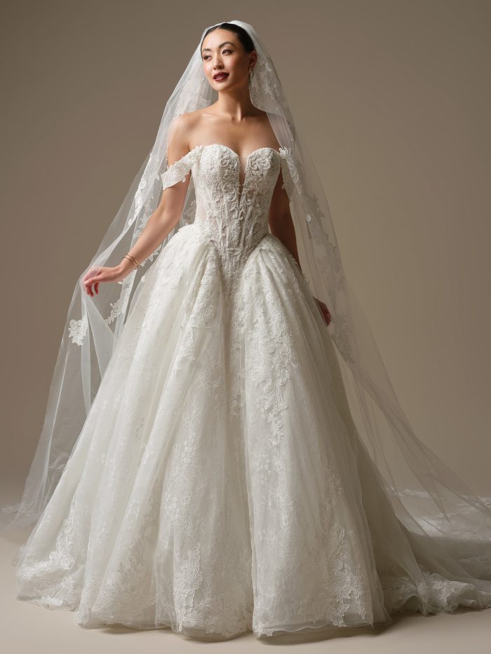 Bride wearing the Zulani veil by Sottero and Midgley, a lace-appliquéd veil with scrolling floral embroidery, paired with an off-the-shoulder lace ball gown wedding dress.