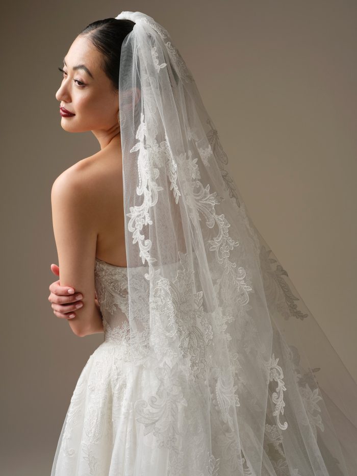 Close-up side view of the Zulani veil by Sottero and Midgley, showing the scrolling floral lace embroidery over a strapless lace ball gown wedding dress.