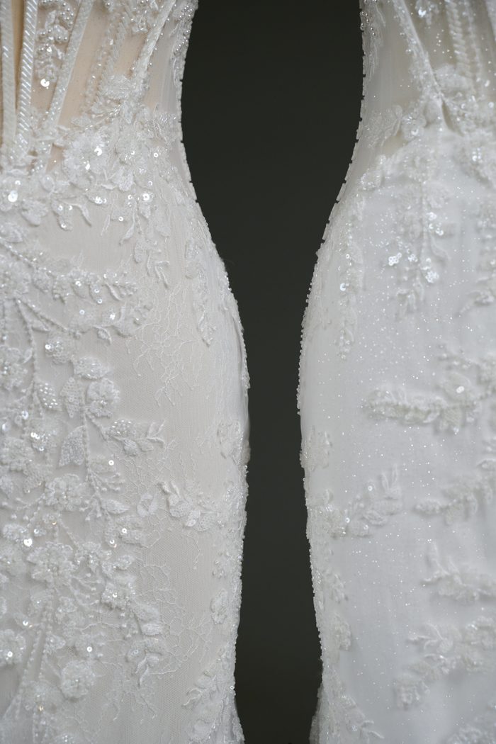 Close-up comparison of the skirt fabric on two Benjie Royale by Maggie Sottero wedding gowns. The gown on the left showcases lace appliqués layered over plain tulle, creating a soft, understated look. The gown on the right features the same lace appliqués over glitter tulle, with visible sparkle throughout the fabric, demonstrating a customizable skirt material option.