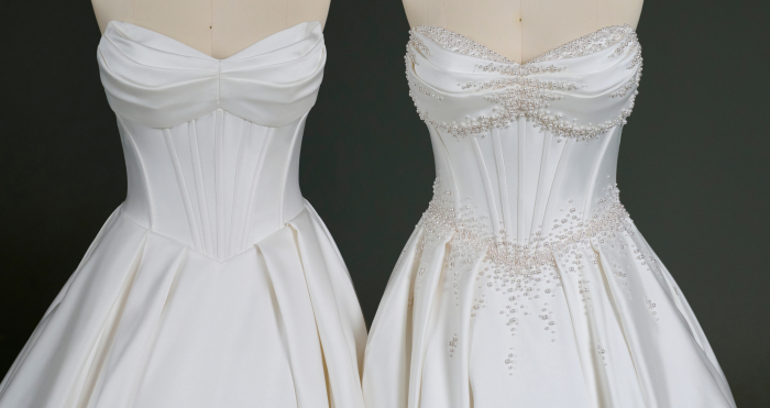 Side-by-side view of the Juneau by Maggie Sottero wedding gown bodice customization. The left gown features a clean satin corset bodice with a draped sweetheart neckline and structured seams, while the right gown showcases the same silhouette embellished with hand-applied pearl beading along the neckline, waist, and skirt. Both gowns are displayed on dress forms against a dark background, highlighting the contrast between the minimalist and embellished designs.