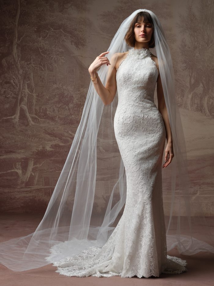 Corazon by Maggie Sottero veil from the Essentials Edit, showcasing a sheer cathedral-length tulle veil draped over a fitted lace wedding gown with a long train.