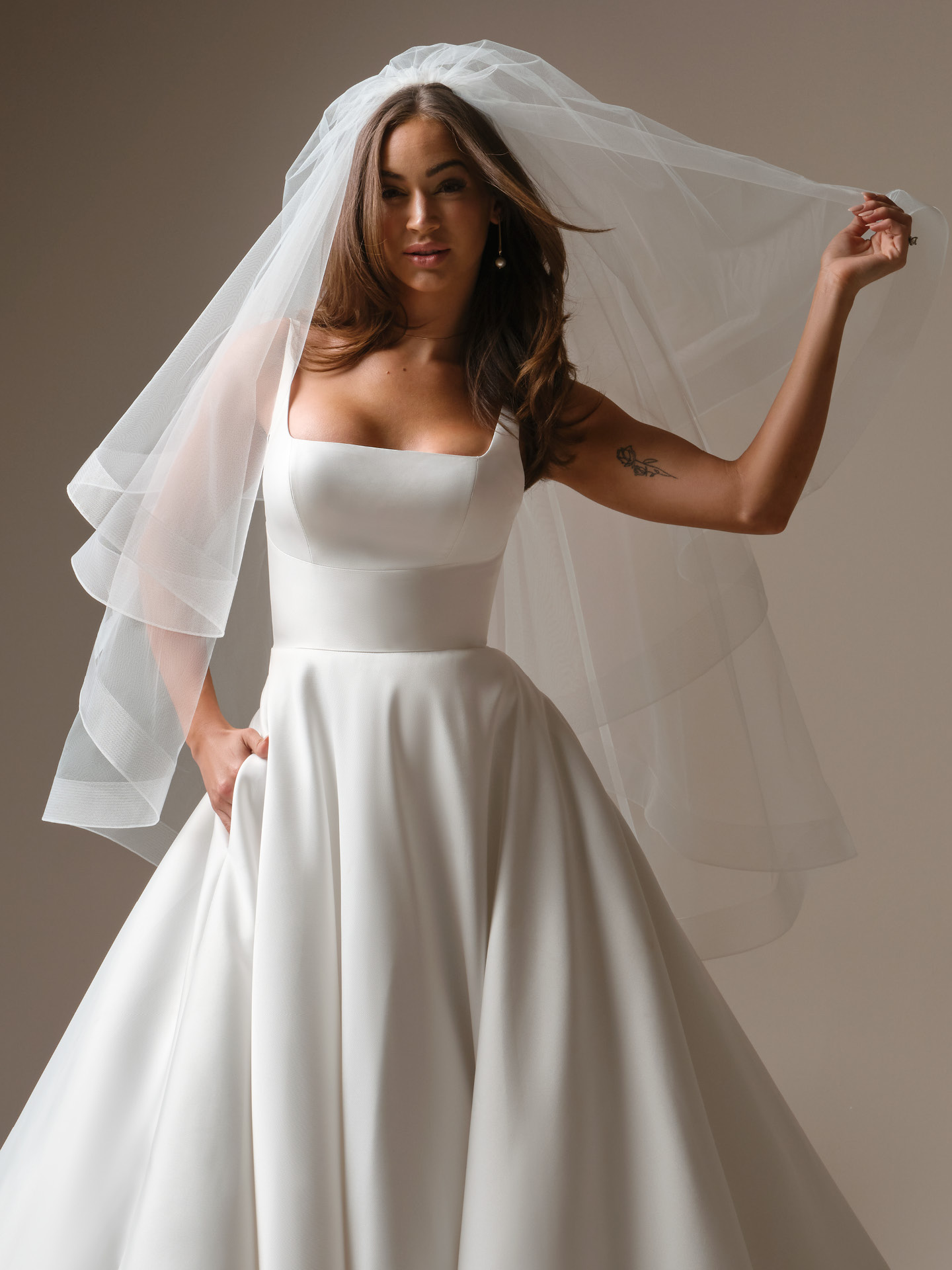 Bride wearing a fingertip tulle veil from the Maggie Sottero Essentials Edit, featuring a soft plain edge layered over a minimalist square-neck satin A-line wedding gown.