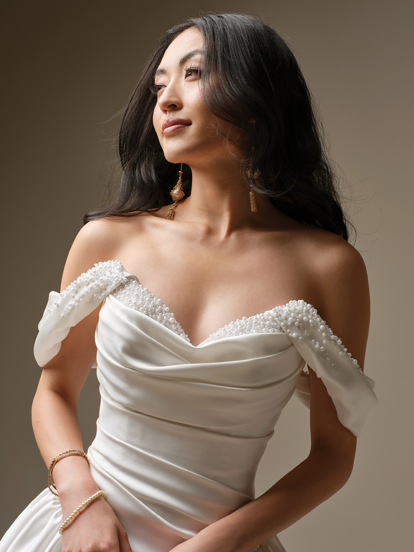 Pasadena satin ballgown wedding dress featuring a draped off-the-shoulder bodice with peekaboo pearl neckline detail.