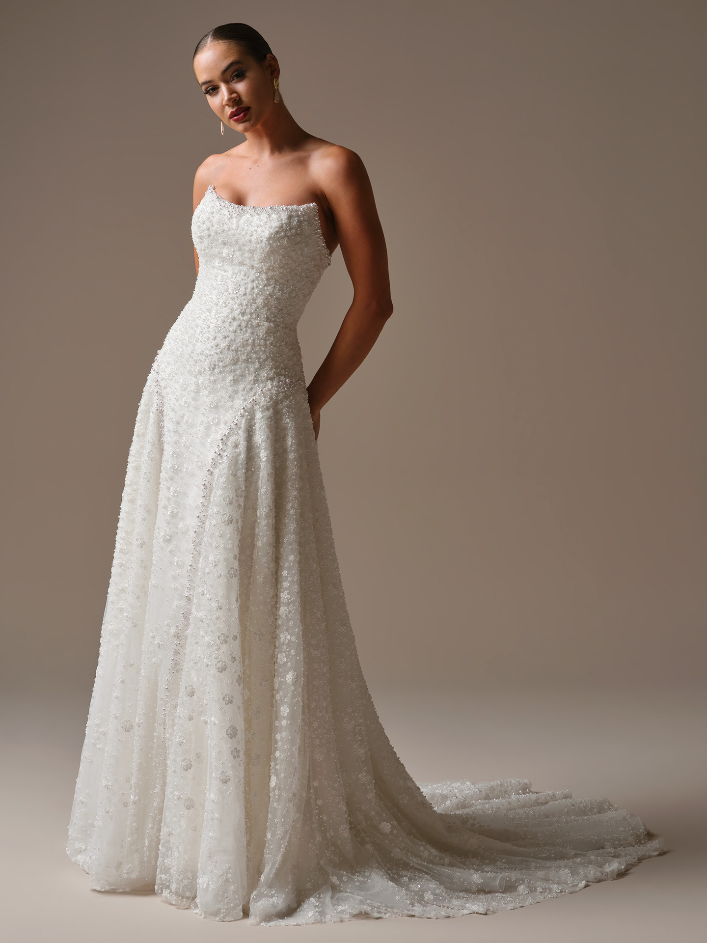 Bride wearing Marceline by Sottero and Midgley, a strapless A-line wedding dress featuring allover beaded lace, a fitted bodice, and a flowing skirt with a soft sparkling train.