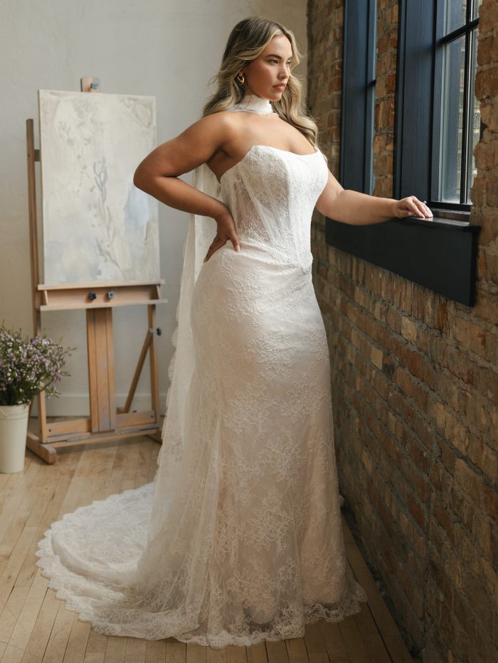 Side view of Maggie Sottero Ariadne sheath wedding dress with a strapless neckline, allover lace, and a sleek, body-skimming silhouette, finished with a delicate train for effortless movement.