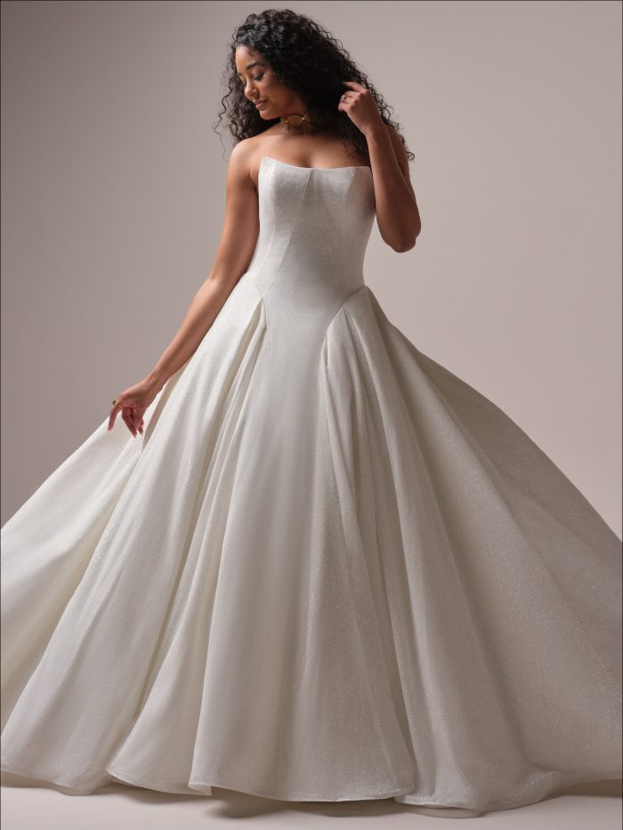 Fortune Royale ballgown wedding dress by Maggie Sottero featuring a strapless cat-eye neckline, basque waist bodice, and full glitter tulle skirt.