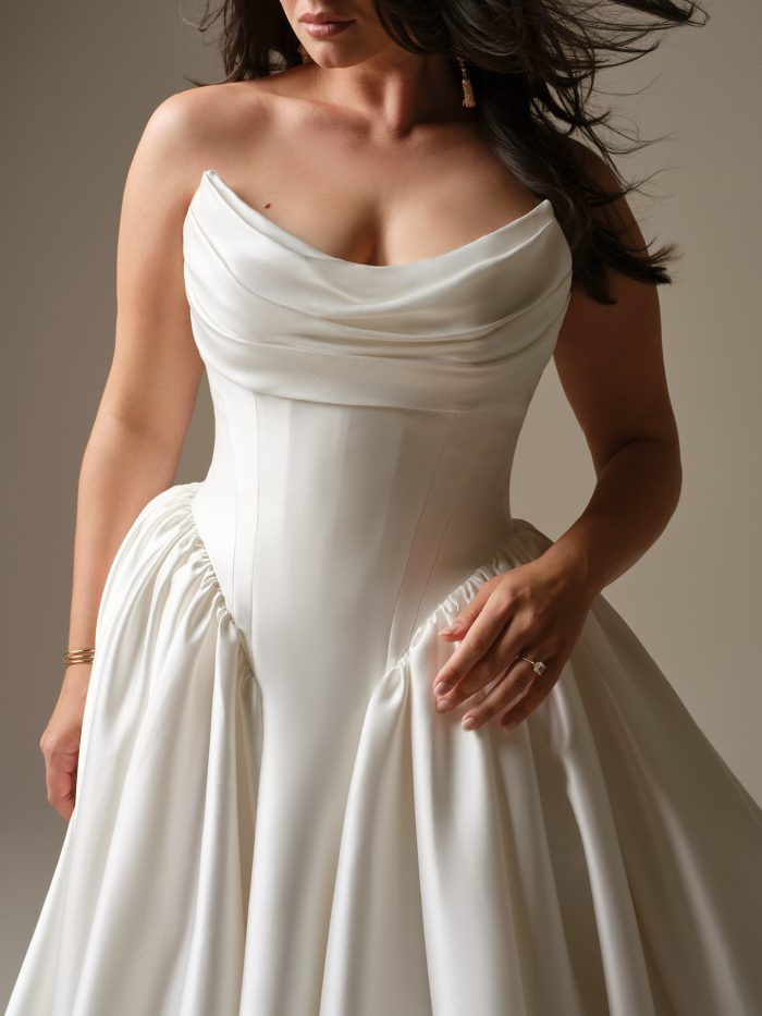 Draped cat-eye neckline wedding dress with structured basque waist and satin ball gown skirt.