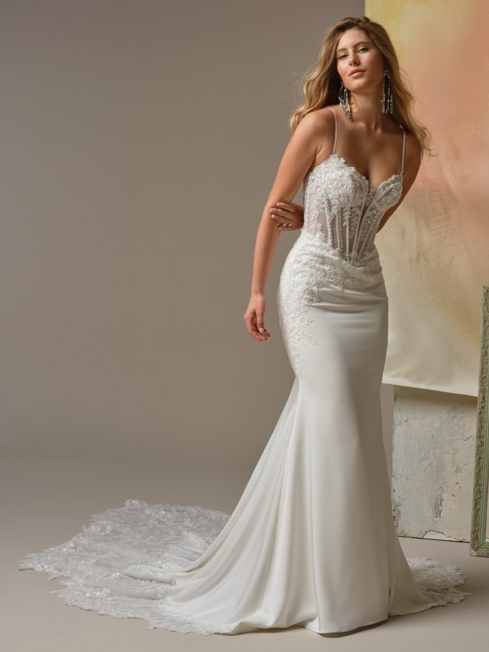 Sheer illusion bodice wedding dress with lace appliqués, spaghetti straps, and fitted sheath skirt with train.