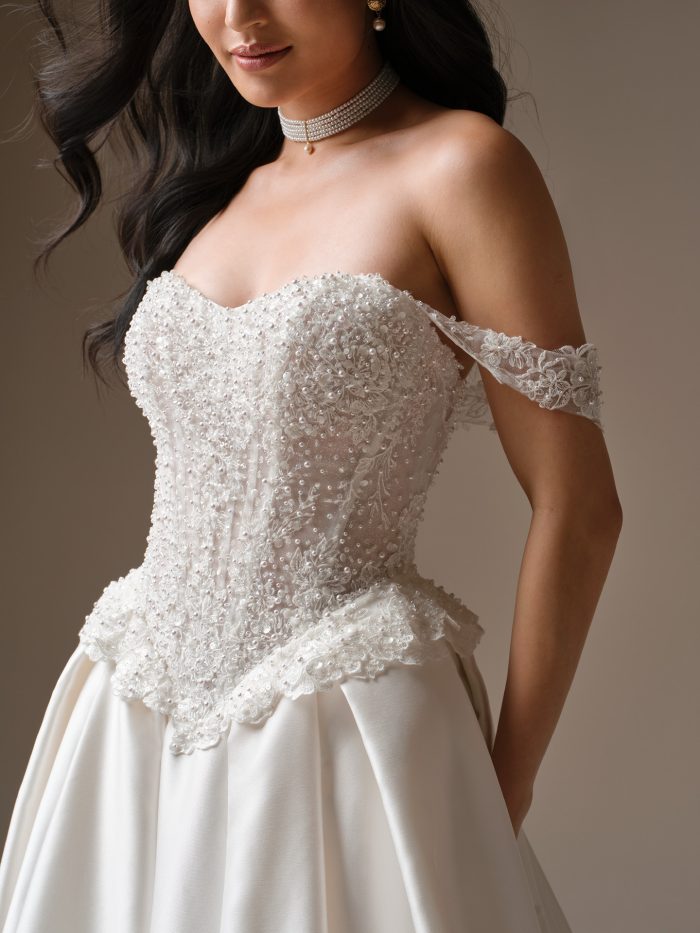 Beaded lace basque waist wedding dress with strapless neckline, off-the-shoulder sleeves, and ball gown skirt.