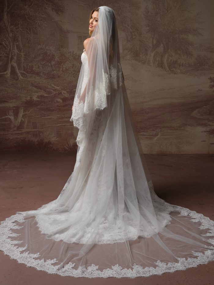 Esmeralda Lane wedding dress and veil by Rebecca Ingram with an allover lace silhouette and delicate straps, paired with a fingertip-length veil with scalloped lace edging, shown in a front view.